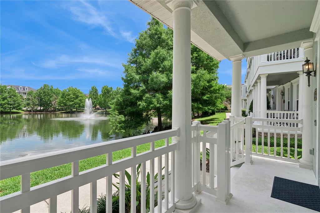 A covered porch with white railings overlooks a pond with a fountain and green trees — 335 LANSBROOK LANE, WINTER SPRINGS, FL