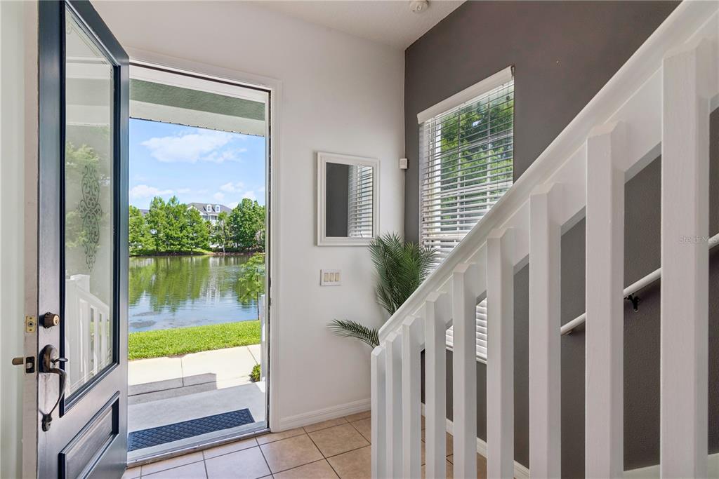 An entryway with tile flooring, a white staircase, and an open door overlooking a lake — 335 LANSBROOK LANE, WINTER SPRINGS, FL