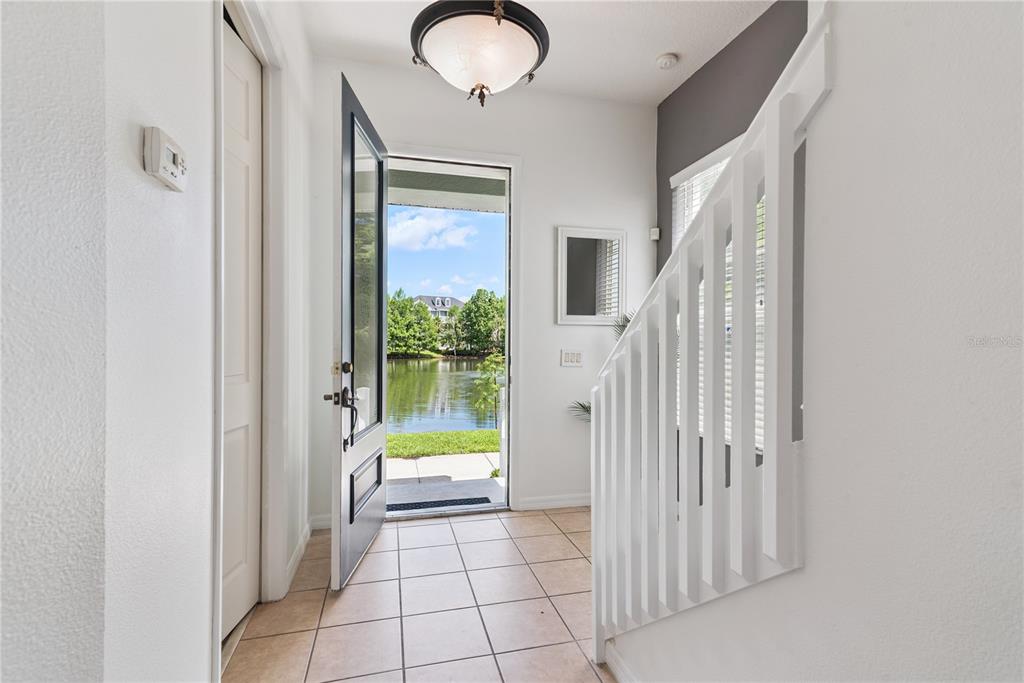 An entryway with tile flooring, a staircase, and an open door revealing a lake view — 335 LANSBROOK LANE, WINTER SPRINGS, FL