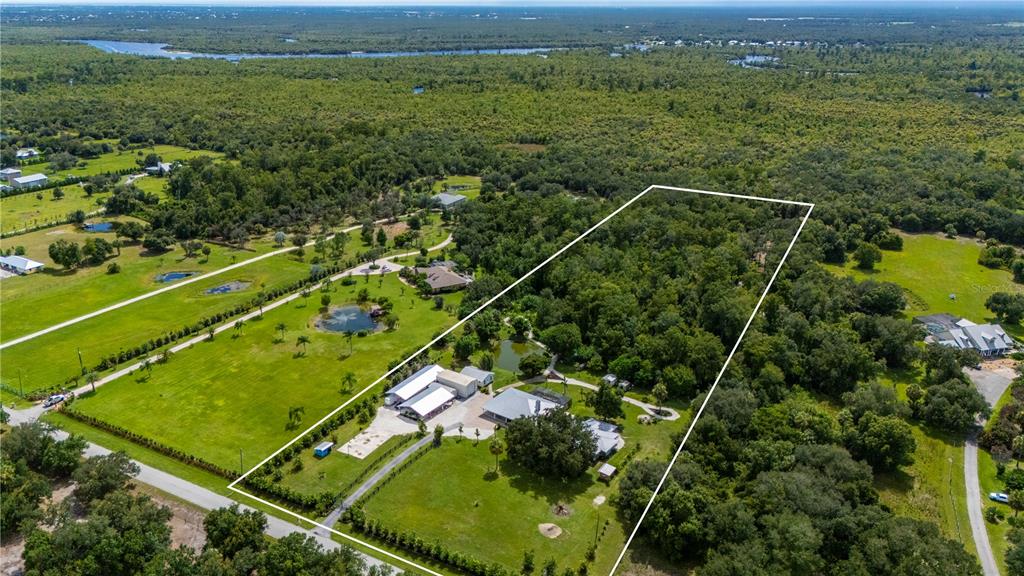 An aerial view shows a rural property with a house, outbuildings, and a large wooded area — 10789 SW CYPRESS BEND AVENUE, ARCADIA, FL