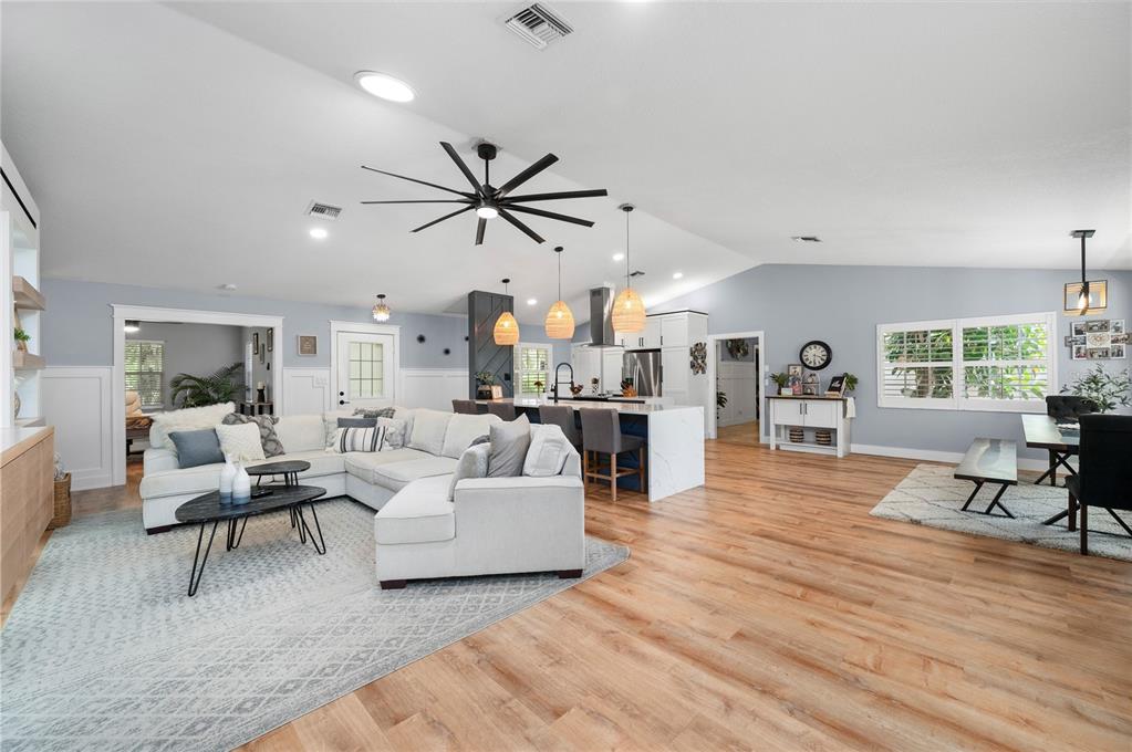 An open-concept living room and kitchen feature light wood floors, white cabinetry, and vaulted ceilings — 10789 SW CYPRESS BEND AVENUE, ARCADIA, FL