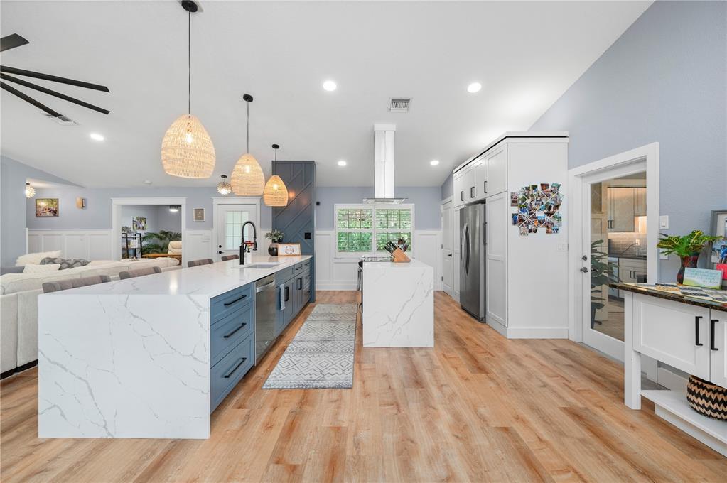 A kitchen features a large marble-topped island, blue cabinetry, and light wood flooring — 10789 SW CYPRESS BEND AVENUE, ARCADIA, FL