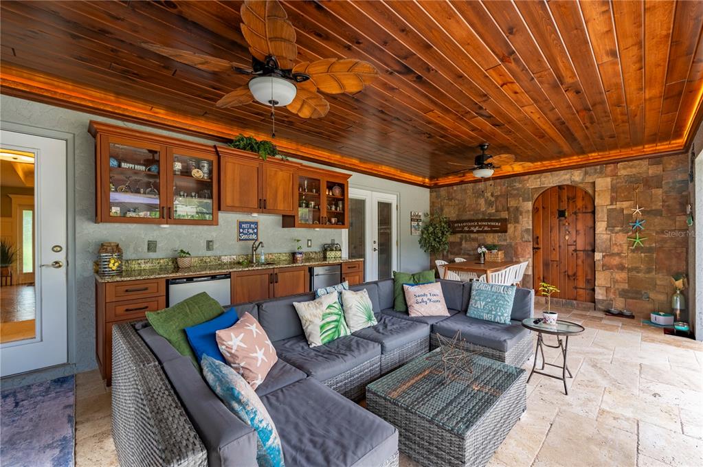 A covered outdoor patio features a kitchenette, sectional seating, and a wood-paneled ceiling — 10789 SW CYPRESS BEND AVENUE, ARCADIA, FL