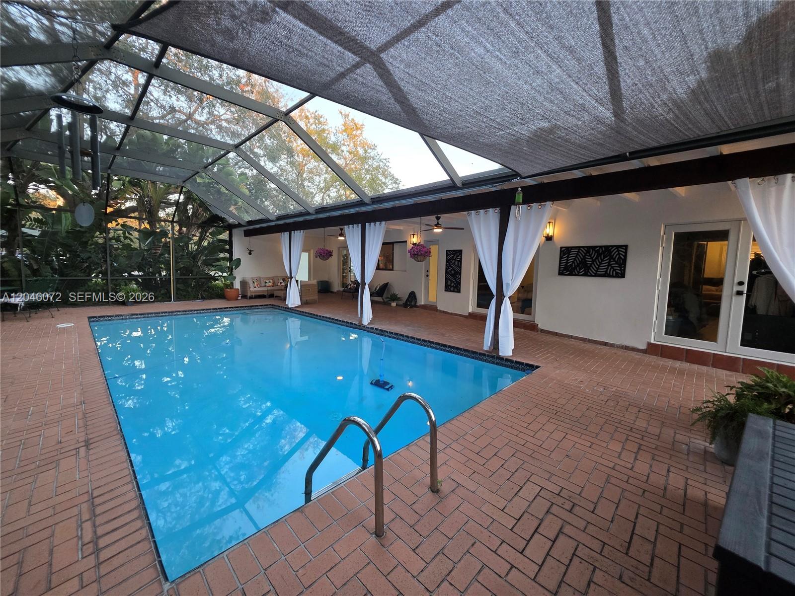 A screened-in patio features a rectangular swimming pool surrounded by red brick pavers — 9860 SW 140th St, Miami FL 33176, MIAMI, FL
