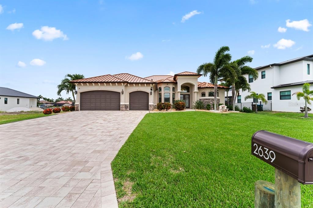 A single-story house with a paved driveway, three-car garage, and a brown metal roof — 2639 SW 29TH AVENUE, CAPE CORAL, FL