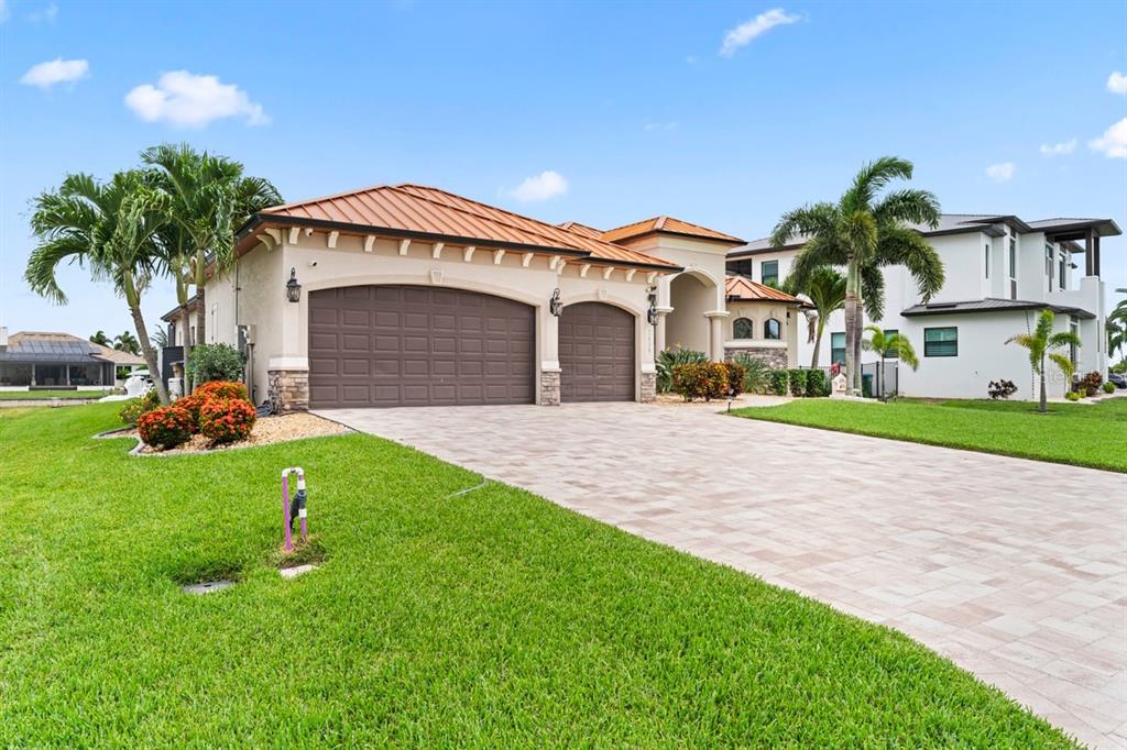 A single-story house with a metal roof, three-car garage, and paved driveway — 2639 SW 29TH AVENUE, CAPE CORAL, FL