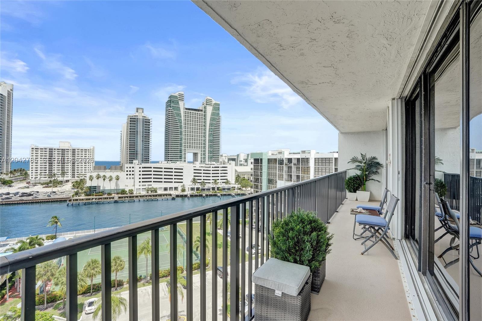 A balcony overlooks a tennis court, a waterway, and high-rise buildings under a blue sky — 400 Leslie Dr # 1110, Hallandale Beach FL 33009, HALLANDALE BEACH, FL