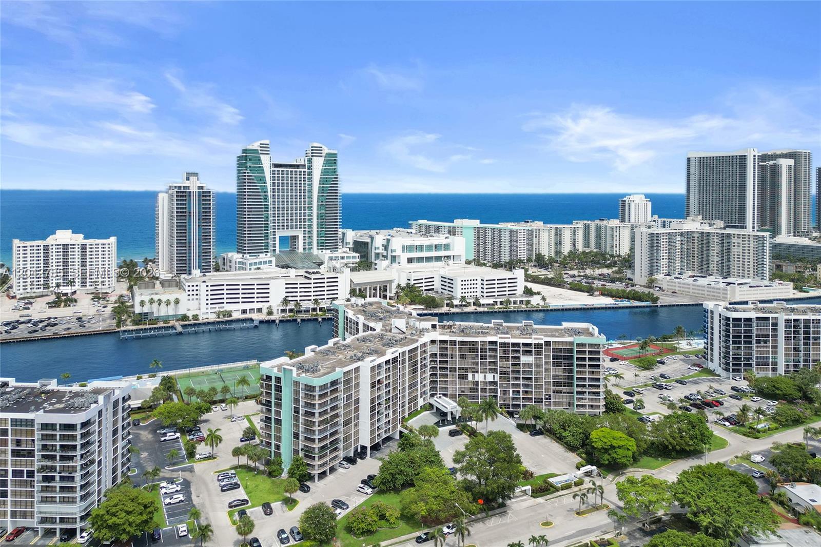 An aerial view shows multiple apartment buildings, a waterway, and the ocean in the distance — 400 Leslie Dr # 1110, Hallandale Beach FL 33009, HALLANDALE BEACH, FL