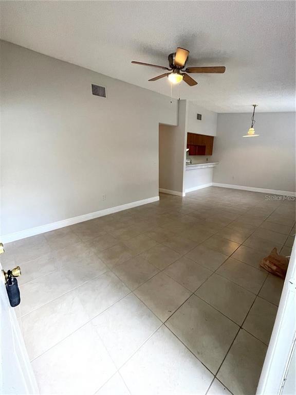 This room features light-colored tile flooring, a ceiling fan, and an open kitchen area — 1916 CRYSTAL GROVE DRIVE, LAKELAND, FL