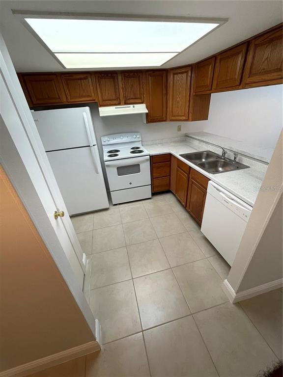 A kitchen features wood cabinets, white appliances, tile flooring, and a recessed ceiling light — 1916 CRYSTAL GROVE DRIVE, LAKELAND, FL
