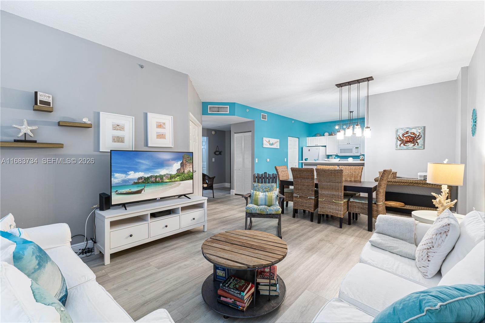 A living room and dining area feature light wood floors, white furniture, and blue walls — 651 Okeechobee Blvd # 202, West Palm Beach FL 33401, WEST PALM BEACH, FL