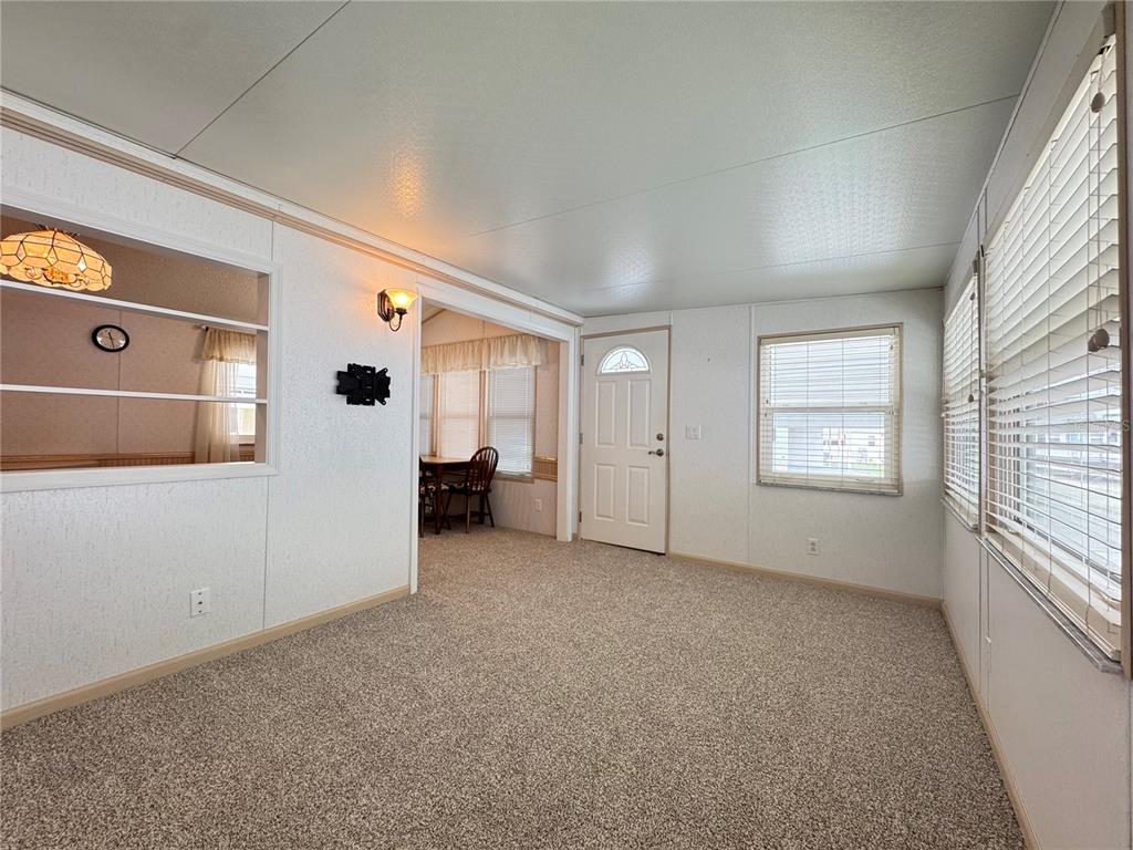 A carpeted living room features white walls, a doorway, and a window with blinds — 4848 BAKER AVENUE UNIT 220, ZEPHYRHILLS, FL