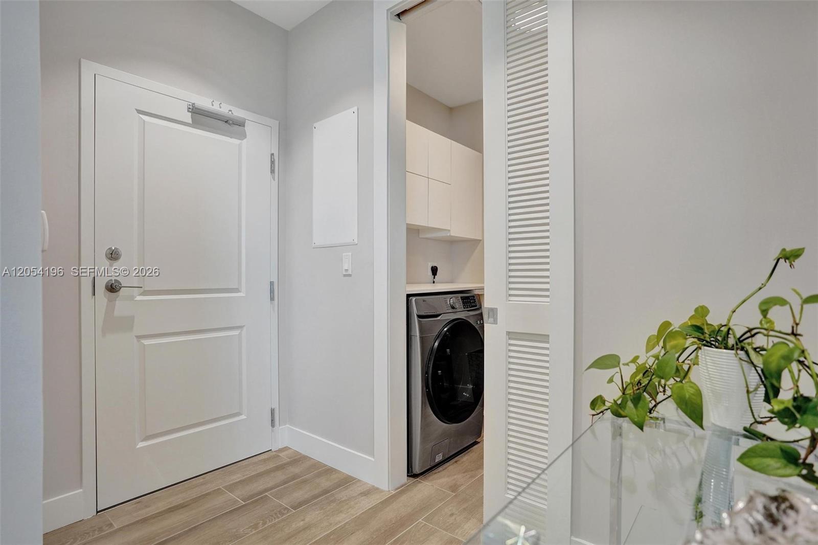 A white door stands next to a laundry closet containing a washer and white cabinets — 41 SW Seminole St # 310, Stuart FL 34994, STUART, FL