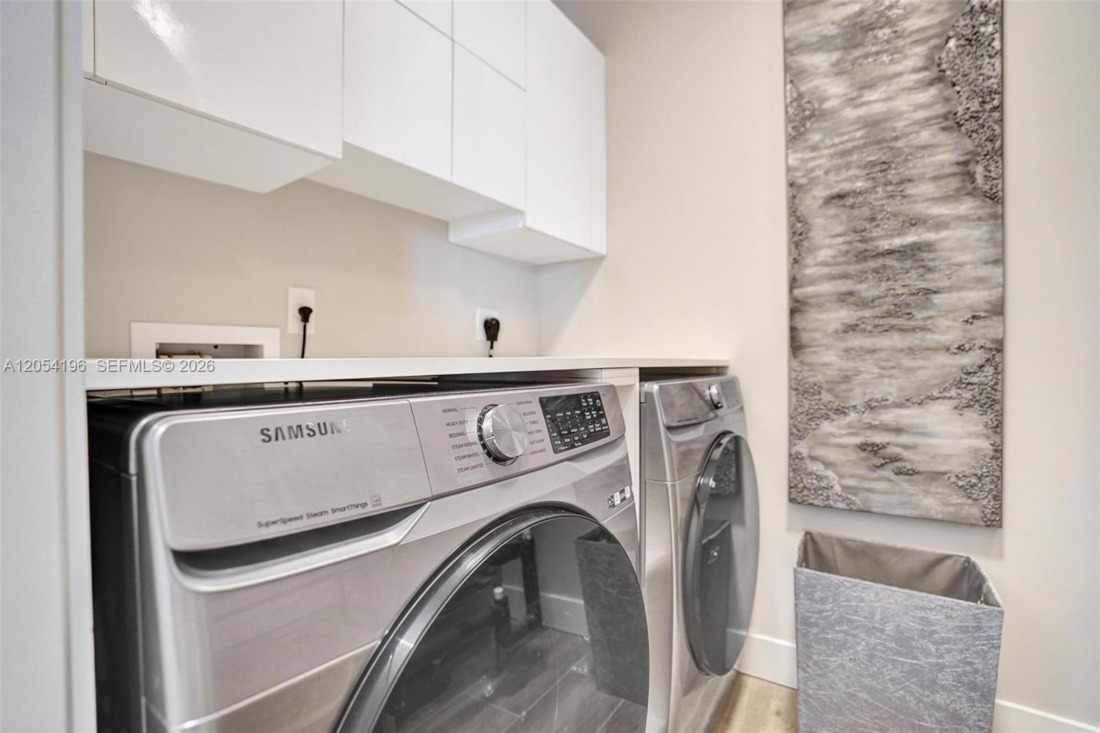 A laundry room features silver Samsung appliances, white upper cabinets, and a textured wall art piece — 41 SW Seminole St # 310, Stuart FL 34994, STUART, FL