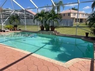 A screened-in swimming pool sits on a patio with a view of a suburban house — 3537 SW 175th Avenue, Miramar FL 33029, MIRAMAR, FL