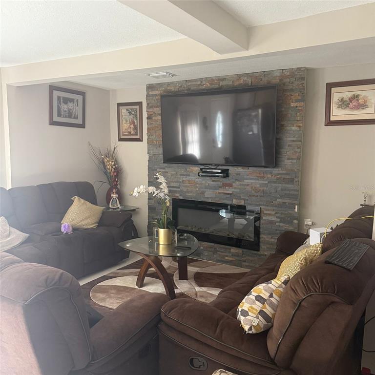 A living room features brown reclining sofas, a glass coffee table, and a stone-tiled fireplace wall — 10004 ETHEL STREET, GIBSONTON, FL