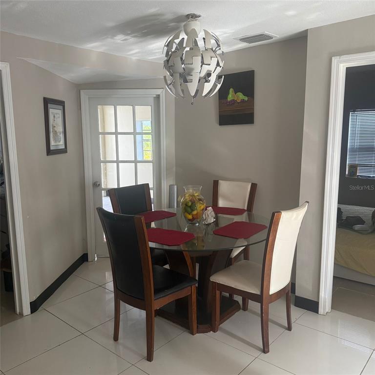 A dining area features a glass-topped table, four chairs, and a modern pendant light fixture — 10004 ETHEL STREET, GIBSONTON, FL