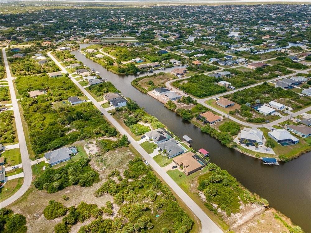 An aerial view shows houses along a canal in a residential neighborhood with native vegetation — 10120 WINNIPEG STREET, PORT CHARLOTTE, FL