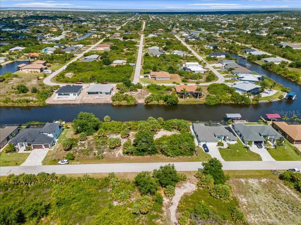 An aerial view shows residential lots and houses situated along a canal in a neighborhood — 10120 WINNIPEG STREET, PORT CHARLOTTE, FL