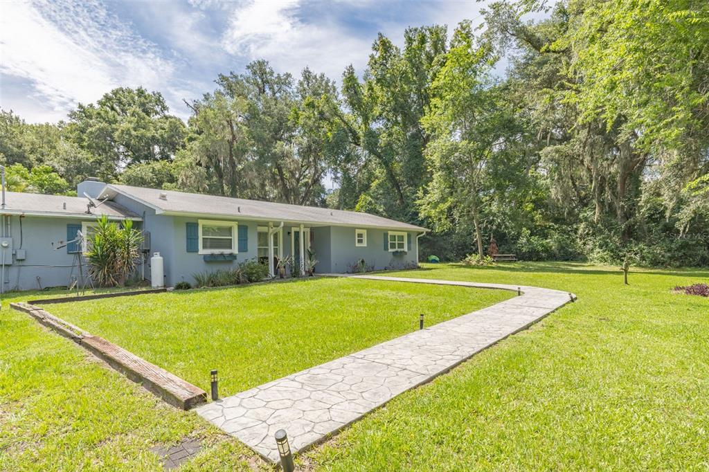 A gray single-story house with a stone walkway leading to the front entrance — 10921 COUNTY ROAD 209, OXFORD, FL