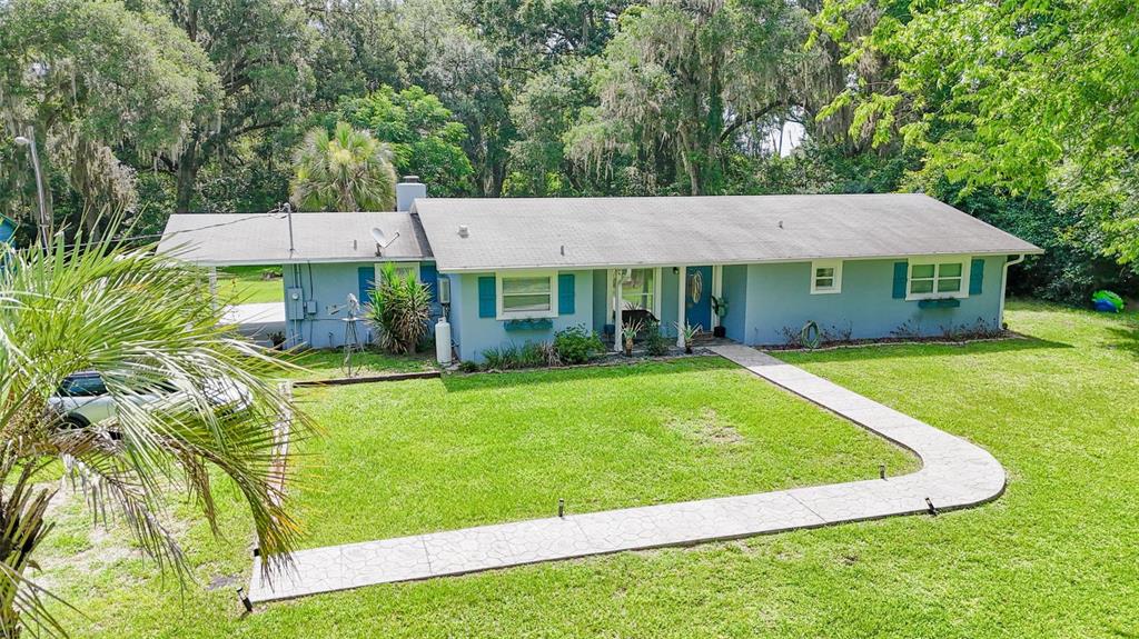 A light blue single-story house with a gray roof and a concrete walkway — 10921 COUNTY ROAD 209, OXFORD, FL