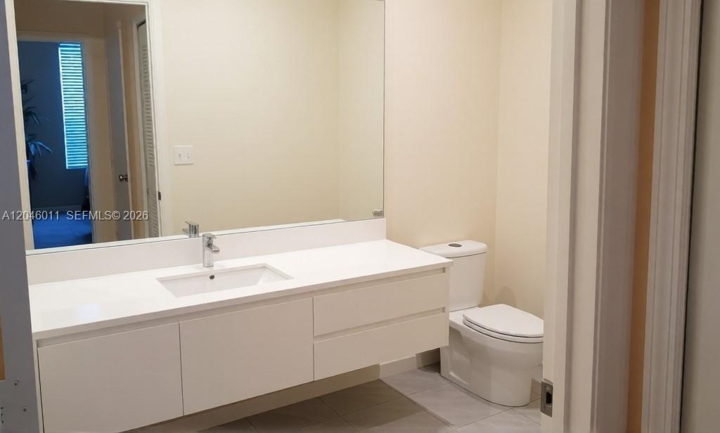 A bathroom features a white floating vanity, a large mirror, and a white toilet — 2788 Almaton Loop # 0, Kissimmee FL 34747, KISSIMMEE, FL