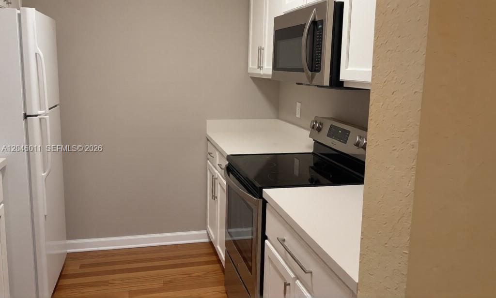 A kitchen features white cabinets, stainless steel appliances, and wood-look flooring — 2788 Almaton Loop # 0, Kissimmee FL 34747, KISSIMMEE, FL