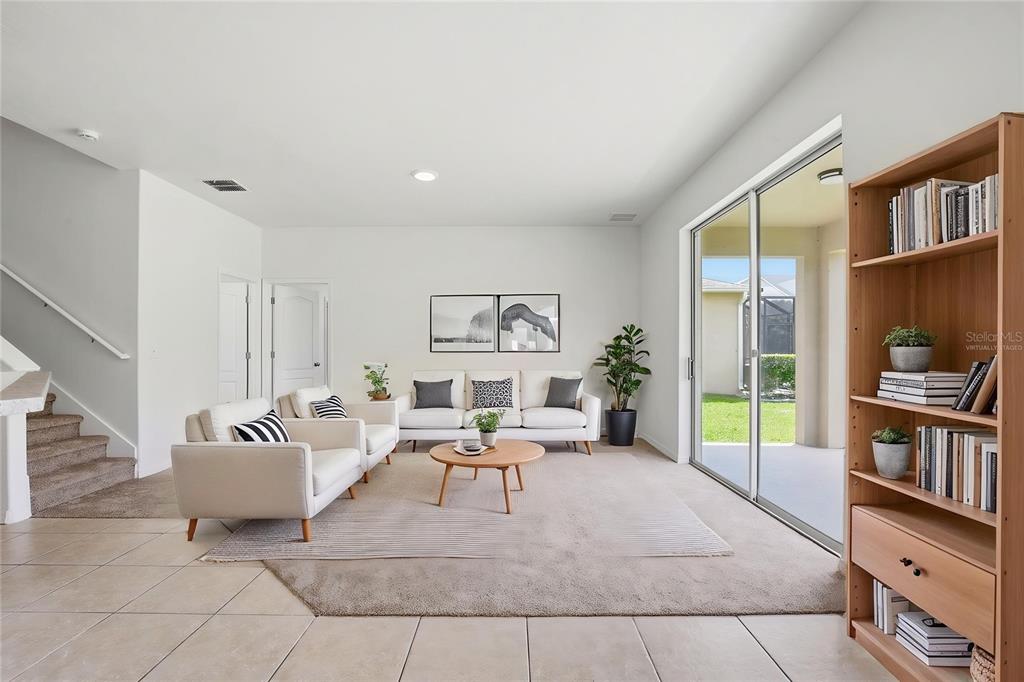 A living room with beige carpet, white walls, a sofa, armchairs, and a sliding glass door — 20506 CAROLINA CHERRY COURT, TAMPA, FL