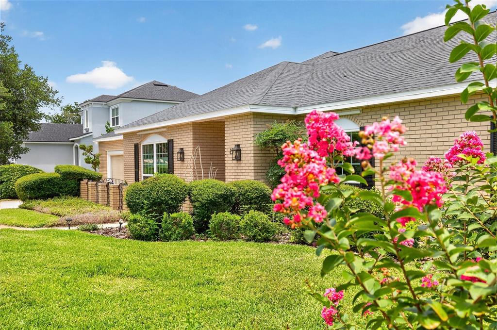 A tan brick house with a gray shingled roof and pink crape myrtle flowers — 15 OAKMONT CIRCLE, ORMOND BEACH, FL