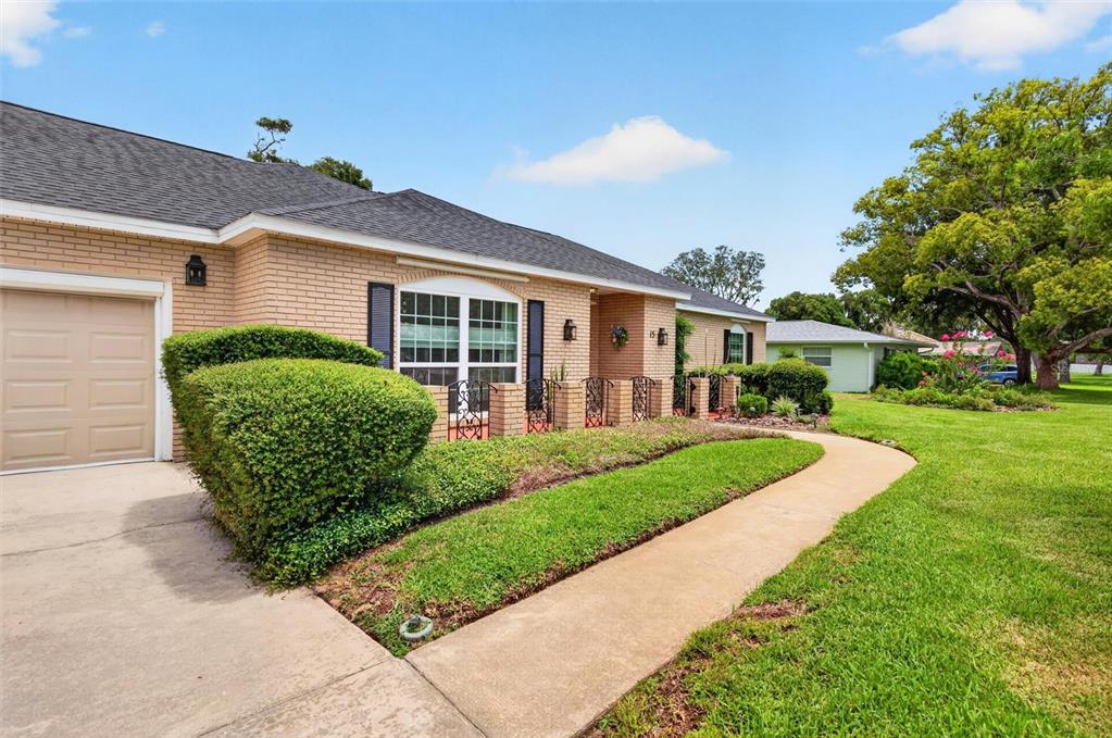 A single-story brick house with a tan garage, green lawn, and a concrete walkway — 15 OAKMONT CIRCLE, ORMOND BEACH, FL