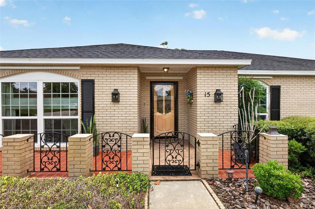 A brick house exterior features a front porch enclosed by decorative black metal gates — 15 OAKMONT CIRCLE, ORMOND BEACH, FL