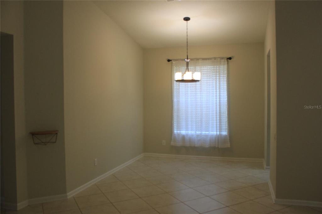 An empty dining room features beige walls, tile flooring, and a hanging light fixture — 7730 BROFIELD AVENUE, WINDERMERE, FL