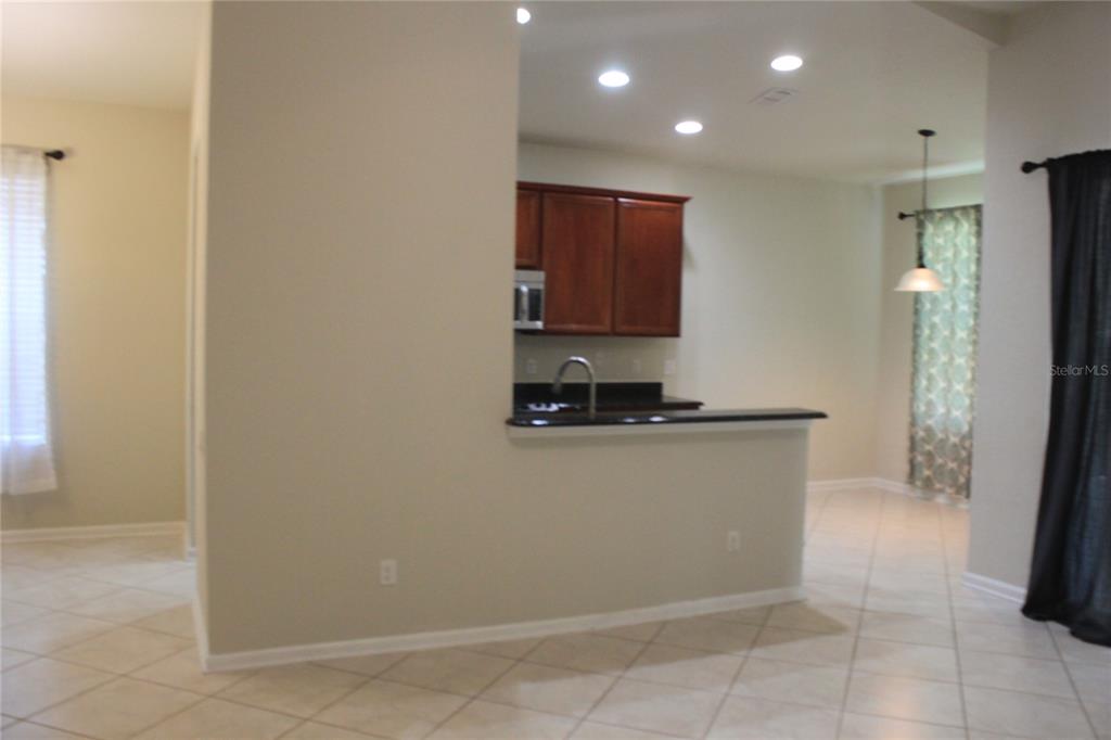 A kitchen with dark wood cabinets and a breakfast bar overlooks a tiled dining area — 7730 BROFIELD AVENUE, WINDERMERE, FL