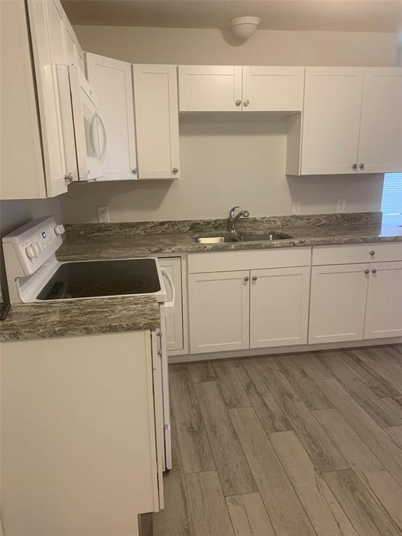 A kitchen with white cabinets, stainless appliances, and light wood-look flooring — 11452 OCEANSPRAY AVENUE, ENGLEWOOD, FL