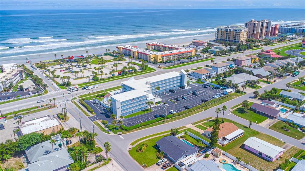 An aerial view shows a multi-story hotel building near a sandy beach and ocean — 3700 S ATLANTIC AVENUE UNIT 215, NEW SMYRNA BEACH, FL