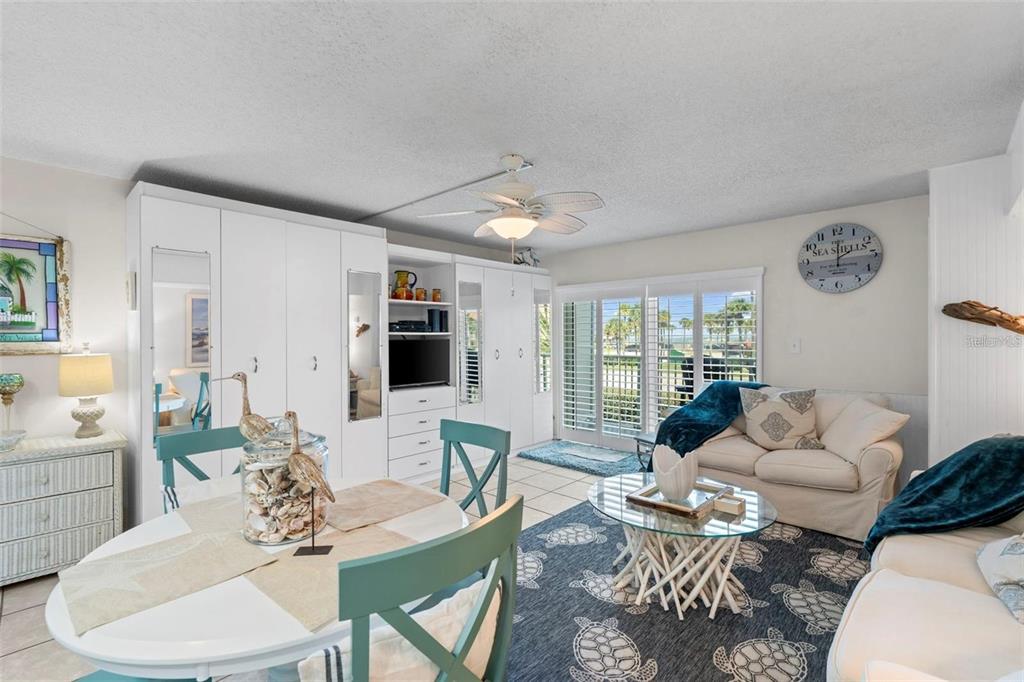 A living and dining area features white cabinetry, a turtle-patterned rug, and sliding glass doors — 3700 S ATLANTIC AVENUE UNIT 215, NEW SMYRNA BEACH, FL