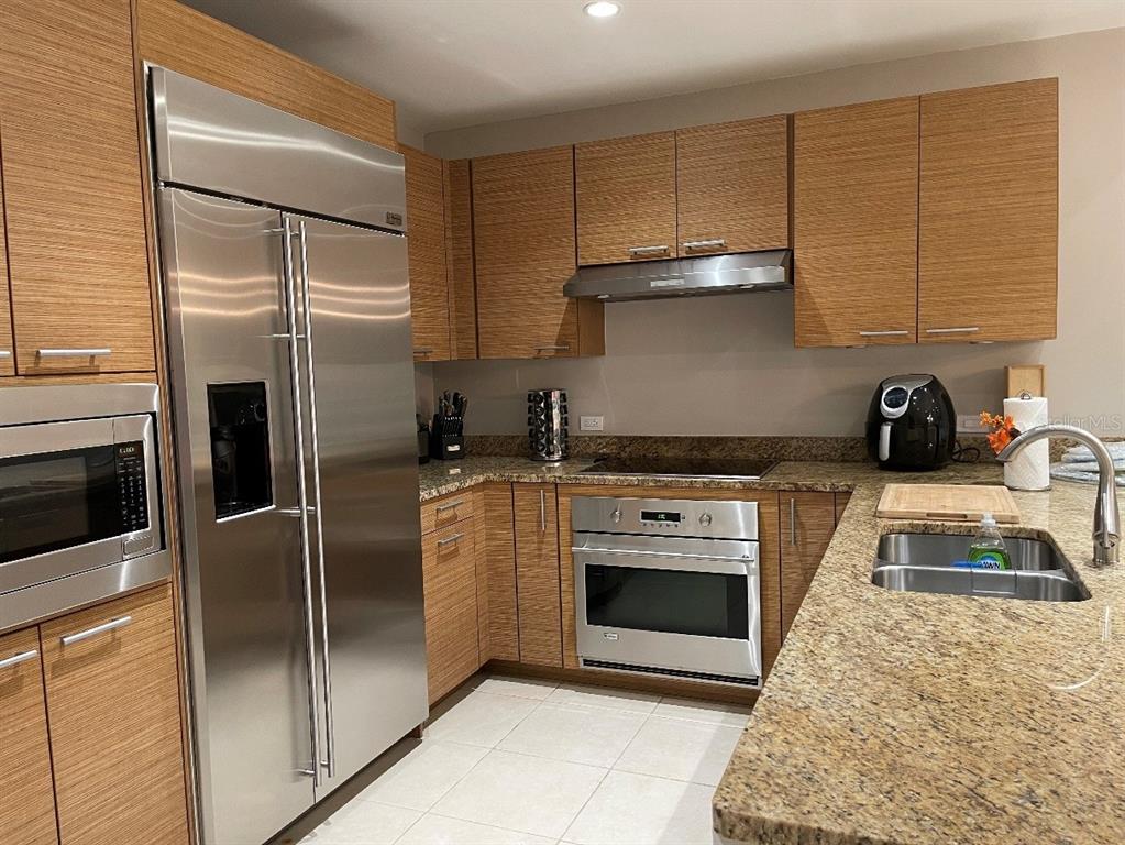 A kitchen with wood-grain cabinets, stainless steel appliances, and granite countertops — 7000 Bahia Beach Blvd LAS VERANDAS CONDOMINIUM UNIT 4128, RIO GRANDE, PR