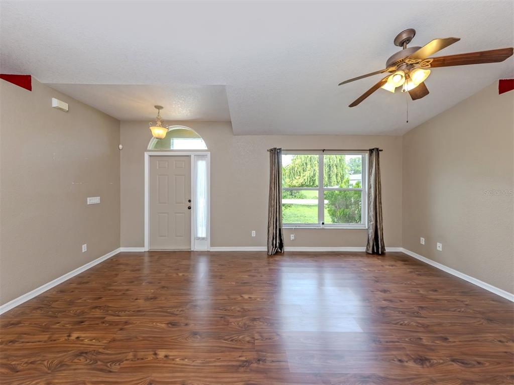 A living room with wood-look flooring, a ceiling fan, and a front entry door — 2136 PENGUIN LANE, NORTH PORT, FL
