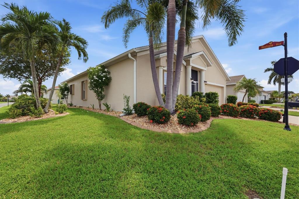 A single-story beige house with a palm tree and landscaping in the front yard — 24195 BUCKINGHAM WAY, PORT CHARLOTTE, FL