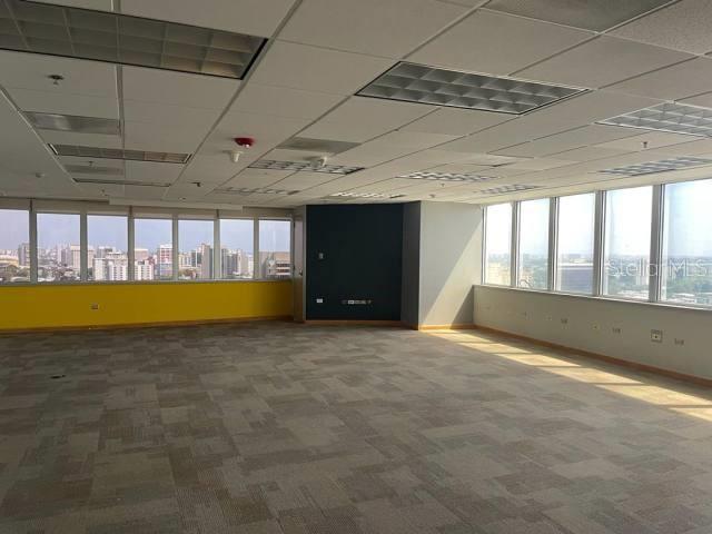 An empty office space features carpeted floors, a drop ceiling, and large windows with city views — 654 MUÑOZ RIVERA, SAN JUAN, PR