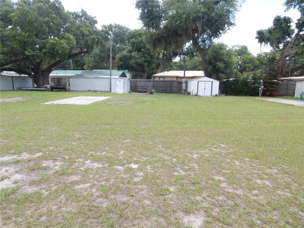 A grassy lot features a concrete pad, a small shed, and a wooden fence — 18 ANCHOR INN ROAD, LAKE WALES, FL