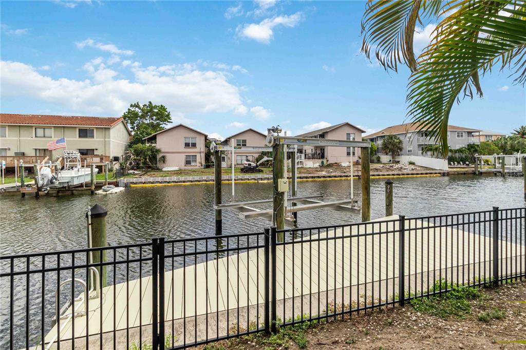 A canal-front property features a private dock, a boat lift, and a black metal fence — 1004 SPINDLE PALM WAY, APOLLO BEACH, FL