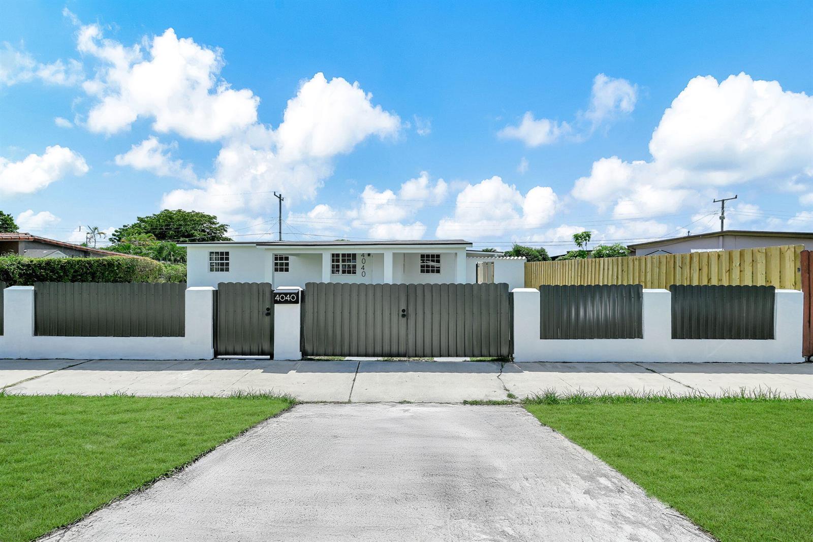 A white single-story house is enclosed by a dark metal fence and a concrete wall — 4040 SW 108th Avenue, Miami FL 33165, MIAMI, FL