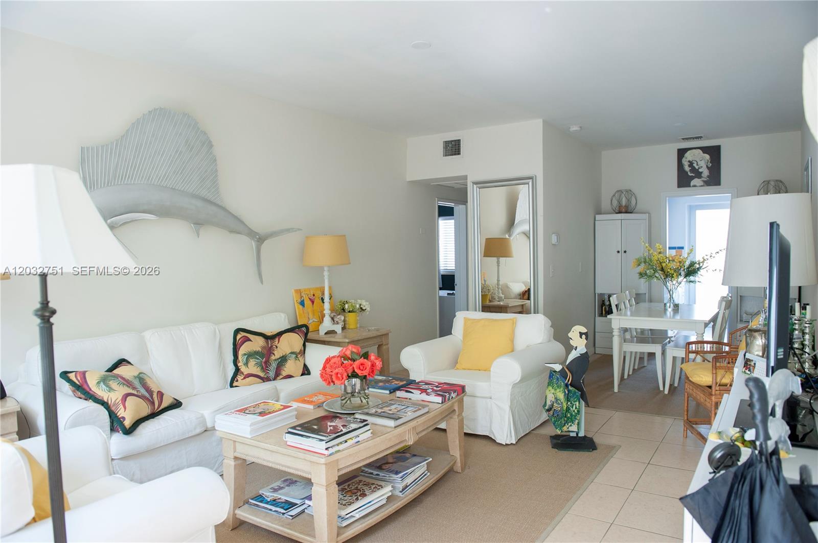 A living room features white sofas, a wooden coffee table, and a large fish wall sculpture — 1840 James Ave # 10, Miami Beach FL 33139, MIAMI BEACH, FL