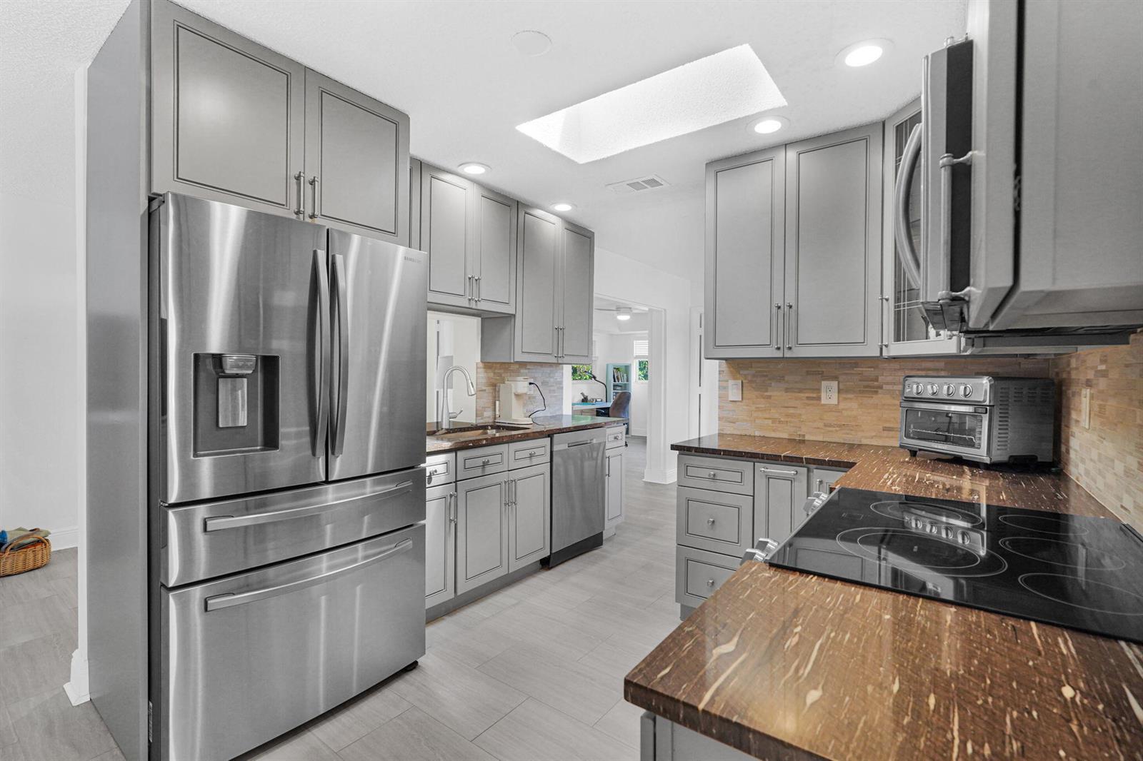 A kitchen features gray cabinets, stainless steel appliances, and brown stone countertops — 1050 NW 73rd Terrace, Margate FL 33063, MARGATE, FL