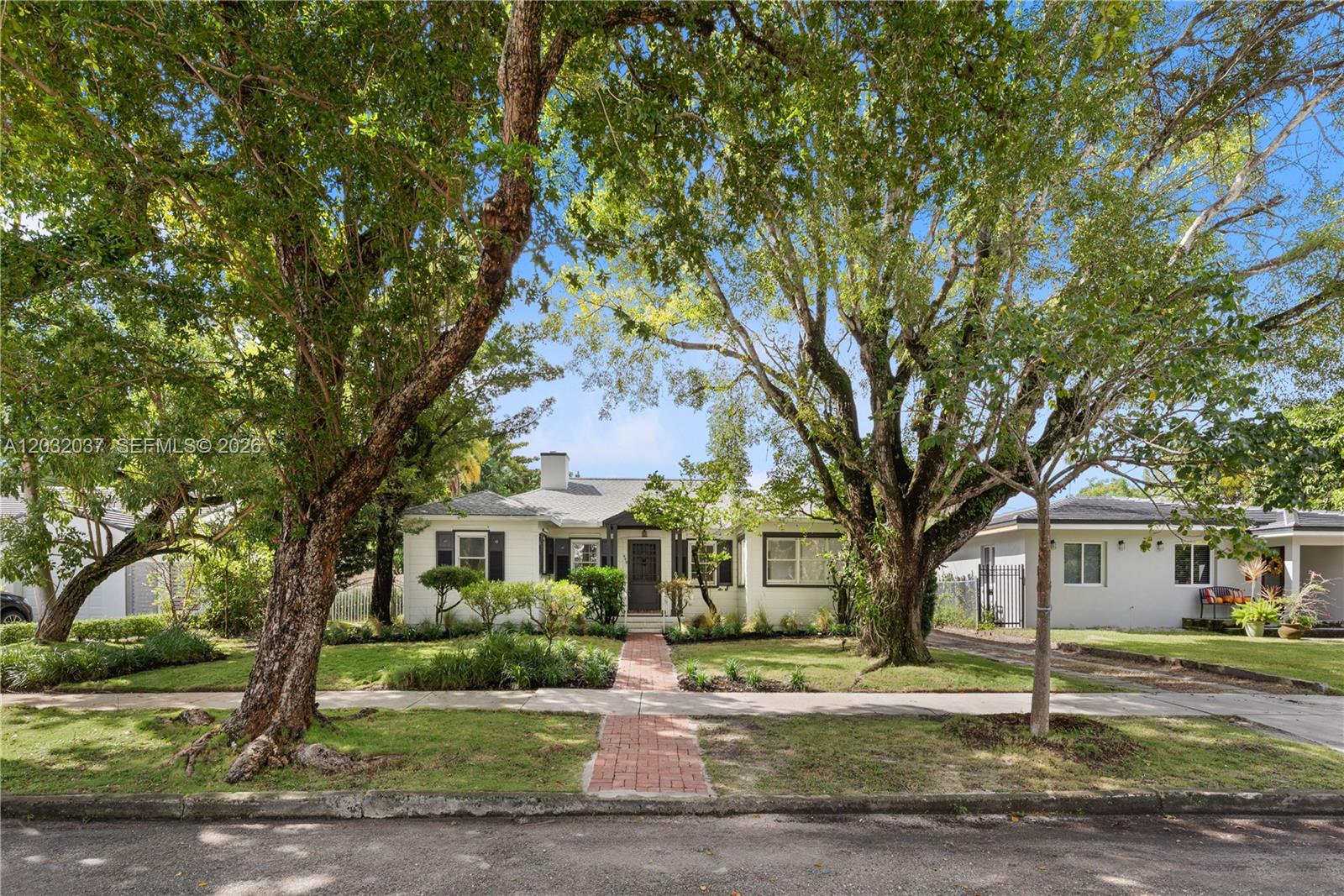 A single-story white house with a brick walkway is framed by two large trees — 440 SW 29th Rd, Miami FL 33129, MIAMI, FL