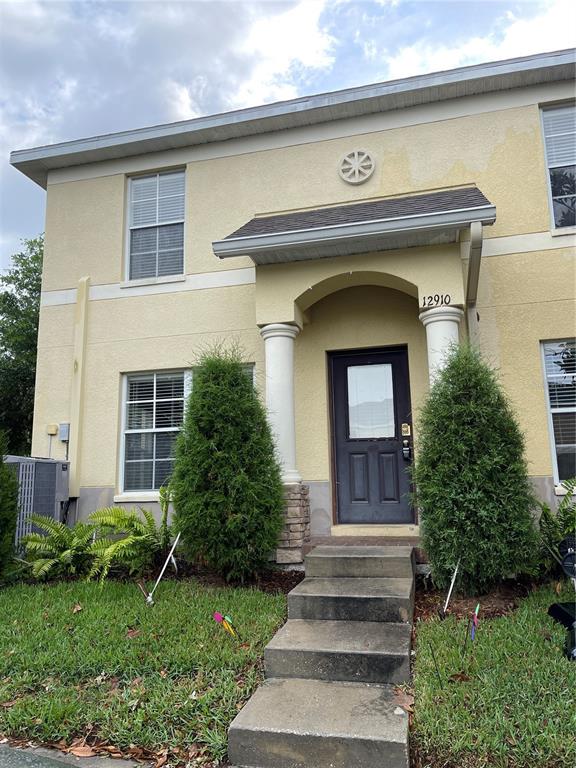 A two-story stucco townhouse features a covered entryway with columns and a dark front door — 12910 JESSUP WATCH PLACE, RIVERVIEW, FL