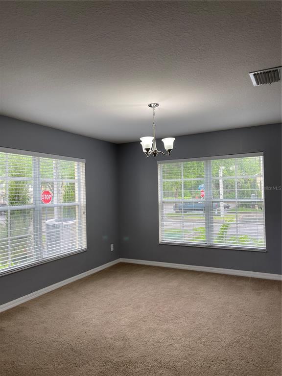 A room with gray walls, beige carpet, a chandelier, and two windows facing a street — 12910 JESSUP WATCH PLACE, RIVERVIEW, FL