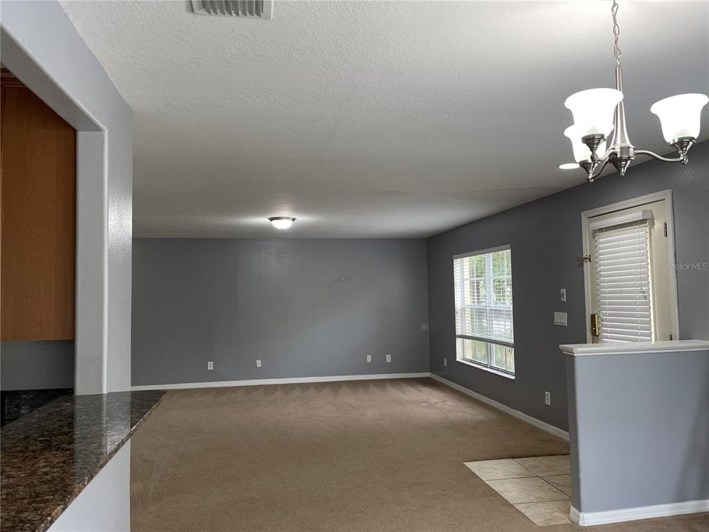 A living room with gray walls, beige carpeting, a ceiling fan, and a chandelier — 12910 JESSUP WATCH PLACE, RIVERVIEW, FL