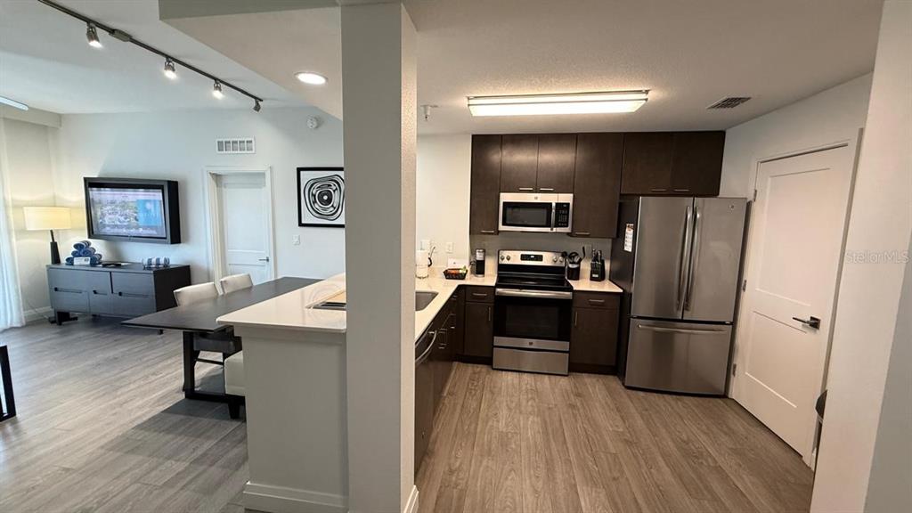 A kitchen with dark cabinets and stainless steel appliances opens to a dining area — 14501 GROVE RESORT AVENUE UNIT 3429, WINTER GARDEN, FL